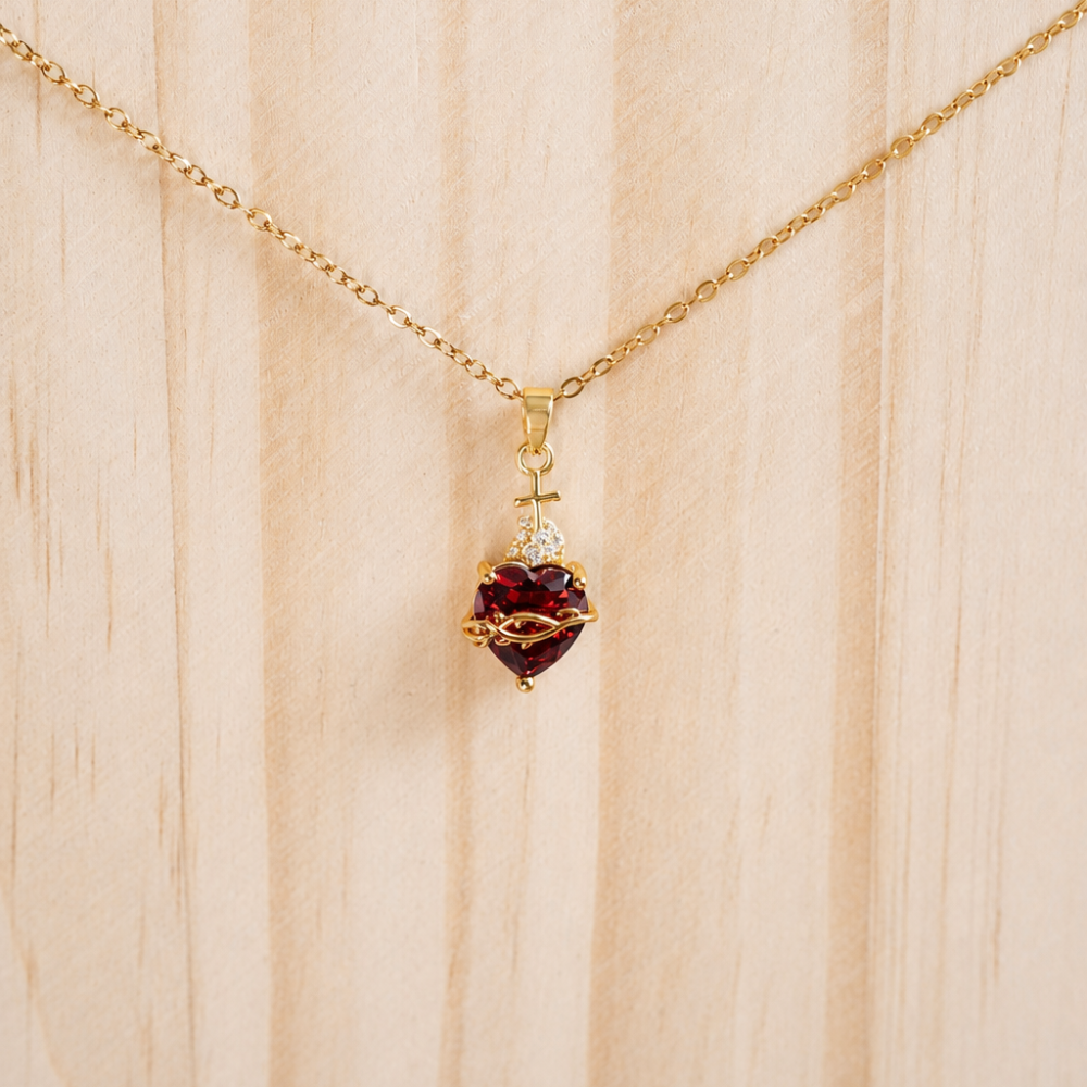 A gold heart pendant necklace with a deep red zircon detail, made from 304 stainless steel with 18k gold PVD coating. Part of the Neréa Anthi Curated Collection.