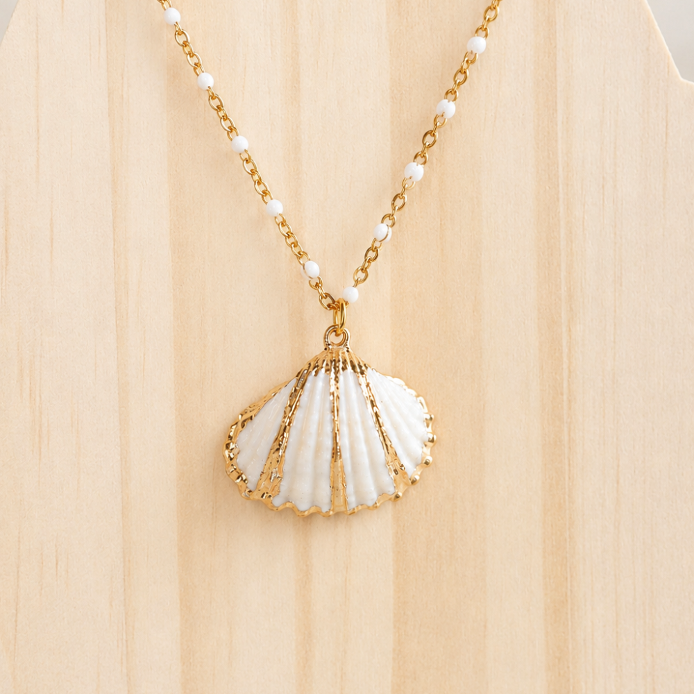 A gold shell necklace with white bead details, made from 304 stainless steel with 18k gold PVD coating. A soft ocean-inspired piece from the Neréa Anthi Curated Collection.