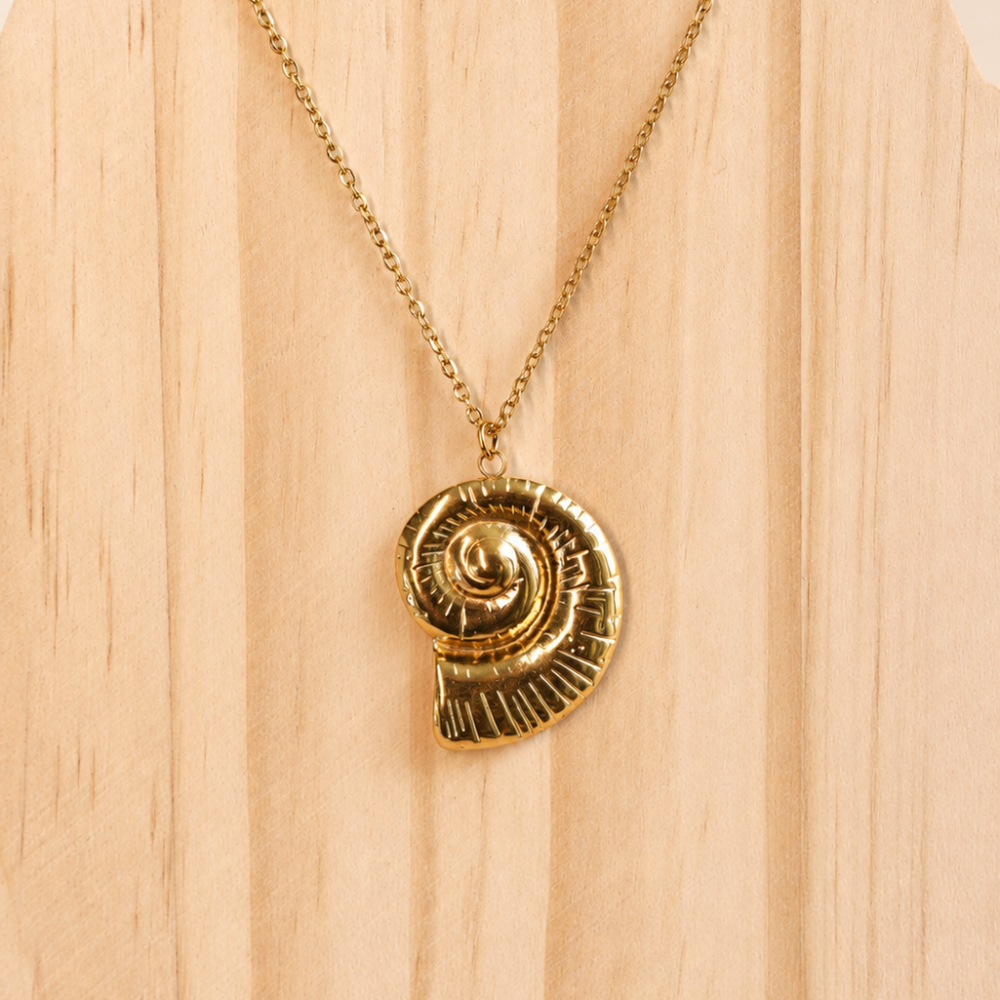 A gold statement necklace with a sculptural ammonite-inspired pendant. An ocean-inspired piece from the Neréa Anthi Curated Collection.