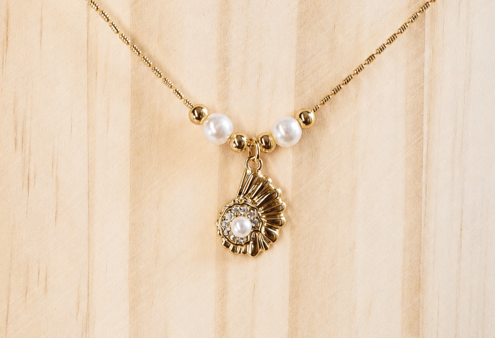 A romantic gold shell necklace with pearl-style beads and sparkling details. A distinctive ocean-inspired piece from the Neréa Anthi Curated Collection.