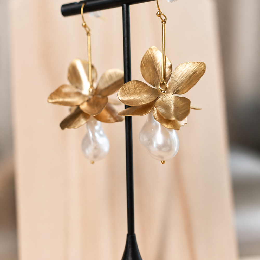 Statement floral drop earrings with sculptural golden petals and pearl-style pendants. An elegant botanical design from the Neréa Anthi Curated Collection.