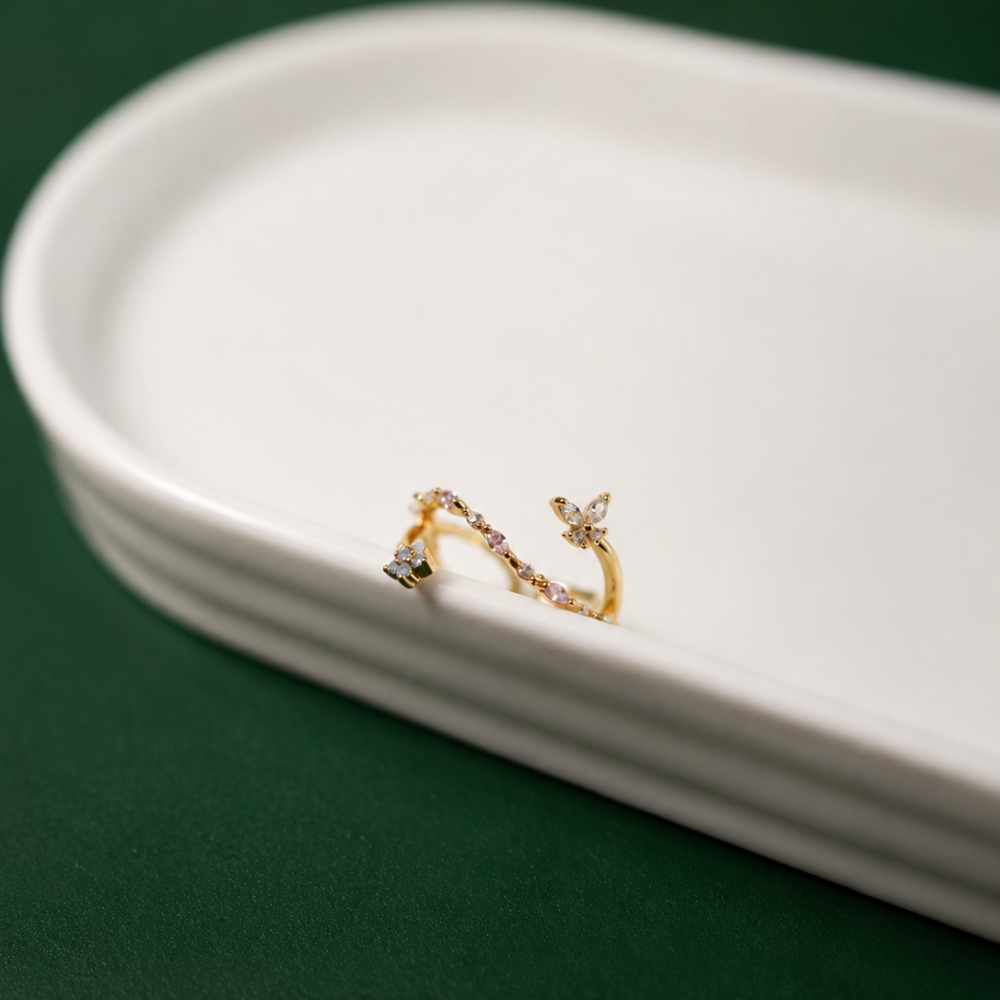 A delicate adjustable gold-plated ring with pink zircon details and a small floral accent. A playful piece from the Neréa Anthi Curated Collection.