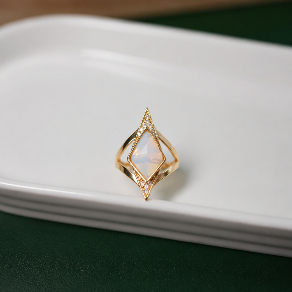 A geometric gold-tone statement ring with an iridescent centre stone and clear zircon details. Part of the Neréa Anthi Curated Collection.