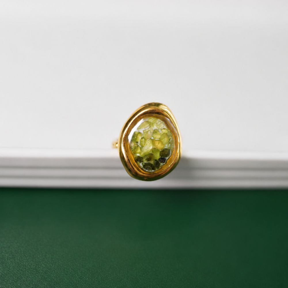 An adjustable 14k gold-plated stainless-steel ring with an organic green enamel centre. A distinctive statement piece from the Curated Collection.