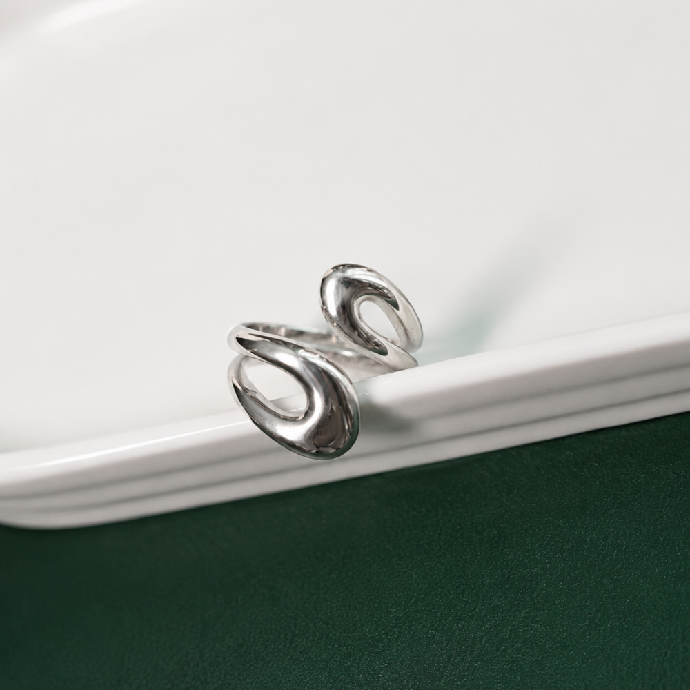 A polished adjustable stainless-steel ring with a fluid, sculptural design. A modern everyday piece from the Neréa Anthi Curated Collection.